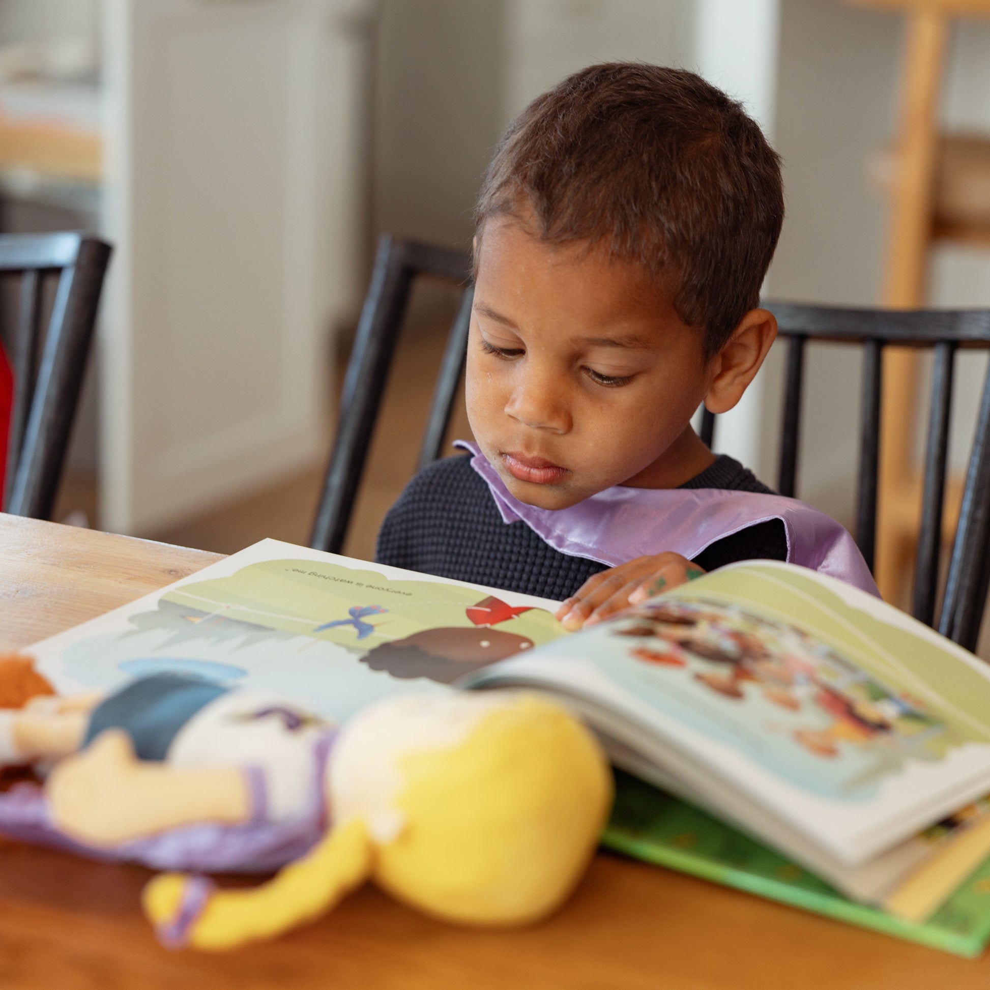 Child reading a Team Supercrew Book with a Chloe the Calm Plush doll nearby