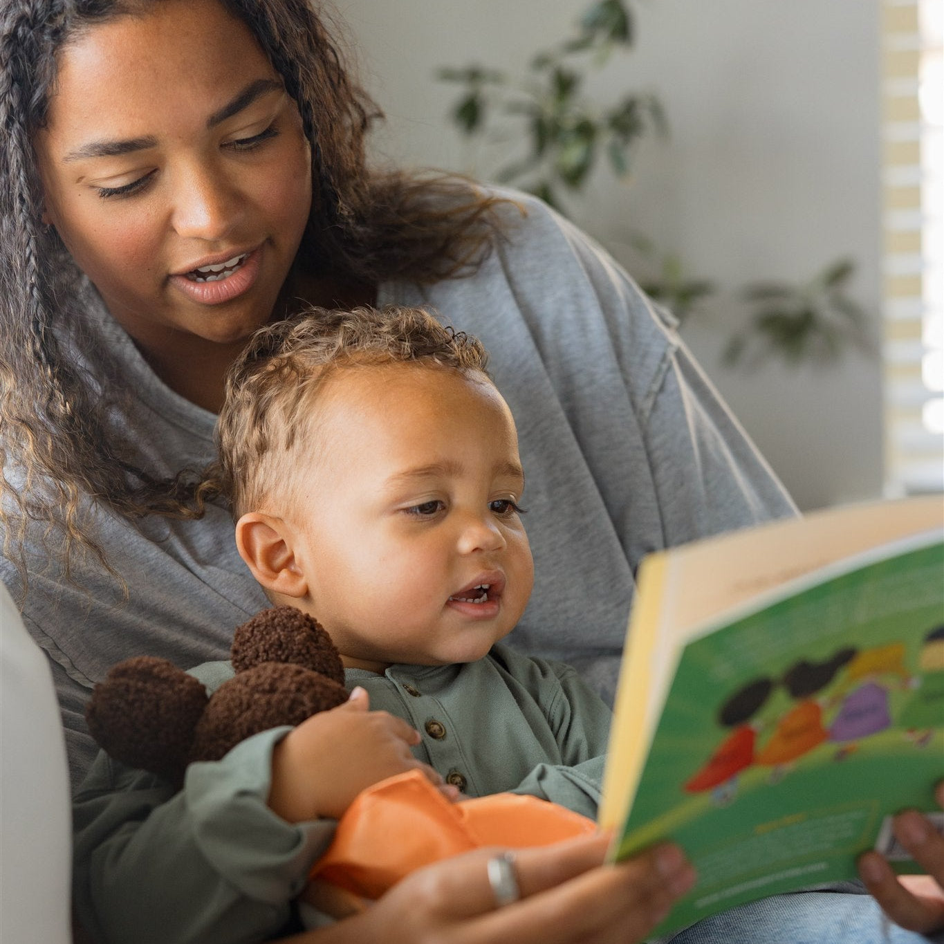 mother and son reading a team supercrew book and holding a keisha the kind plush